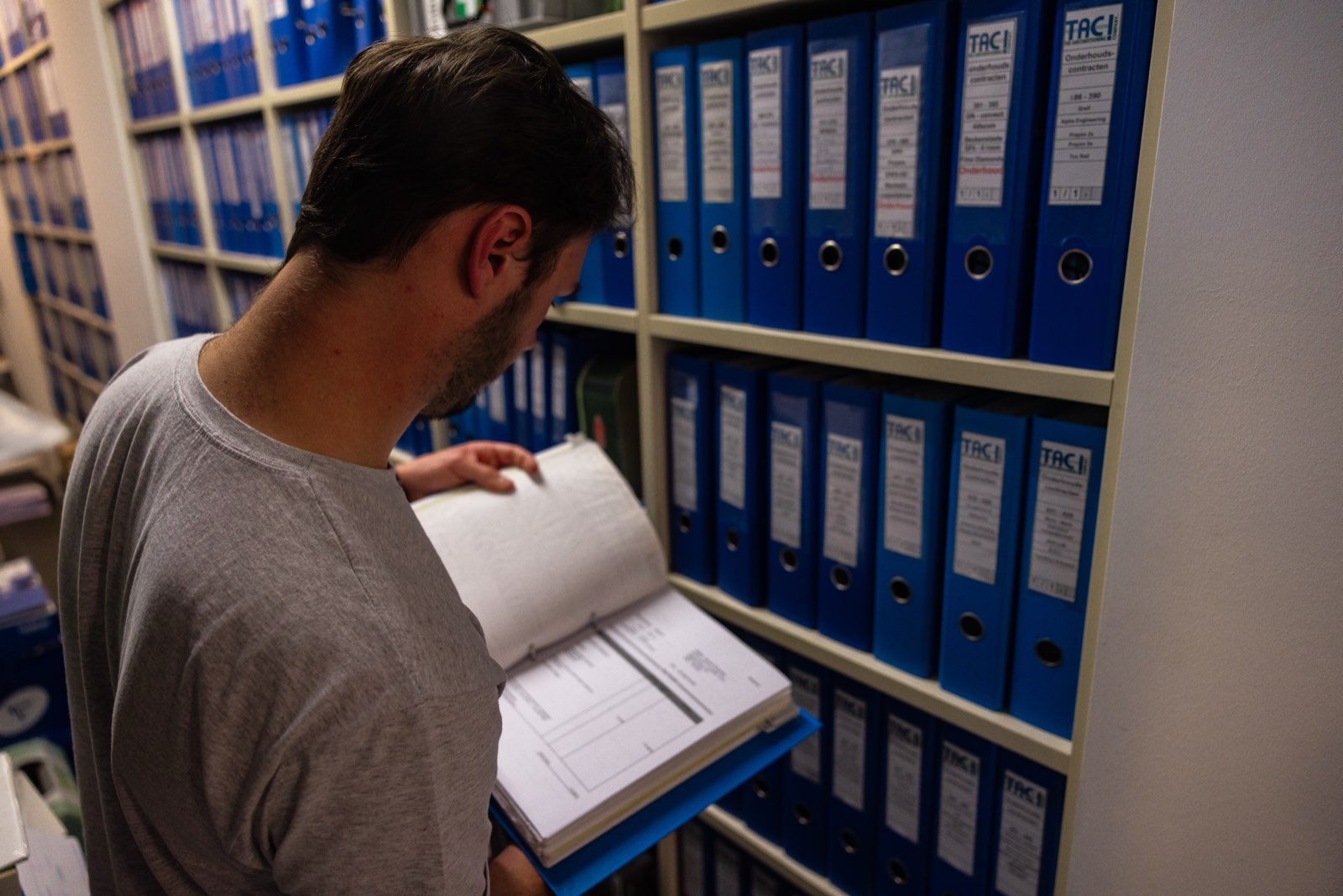 Collega raadpleegt een onderhoudsdossier in het archief