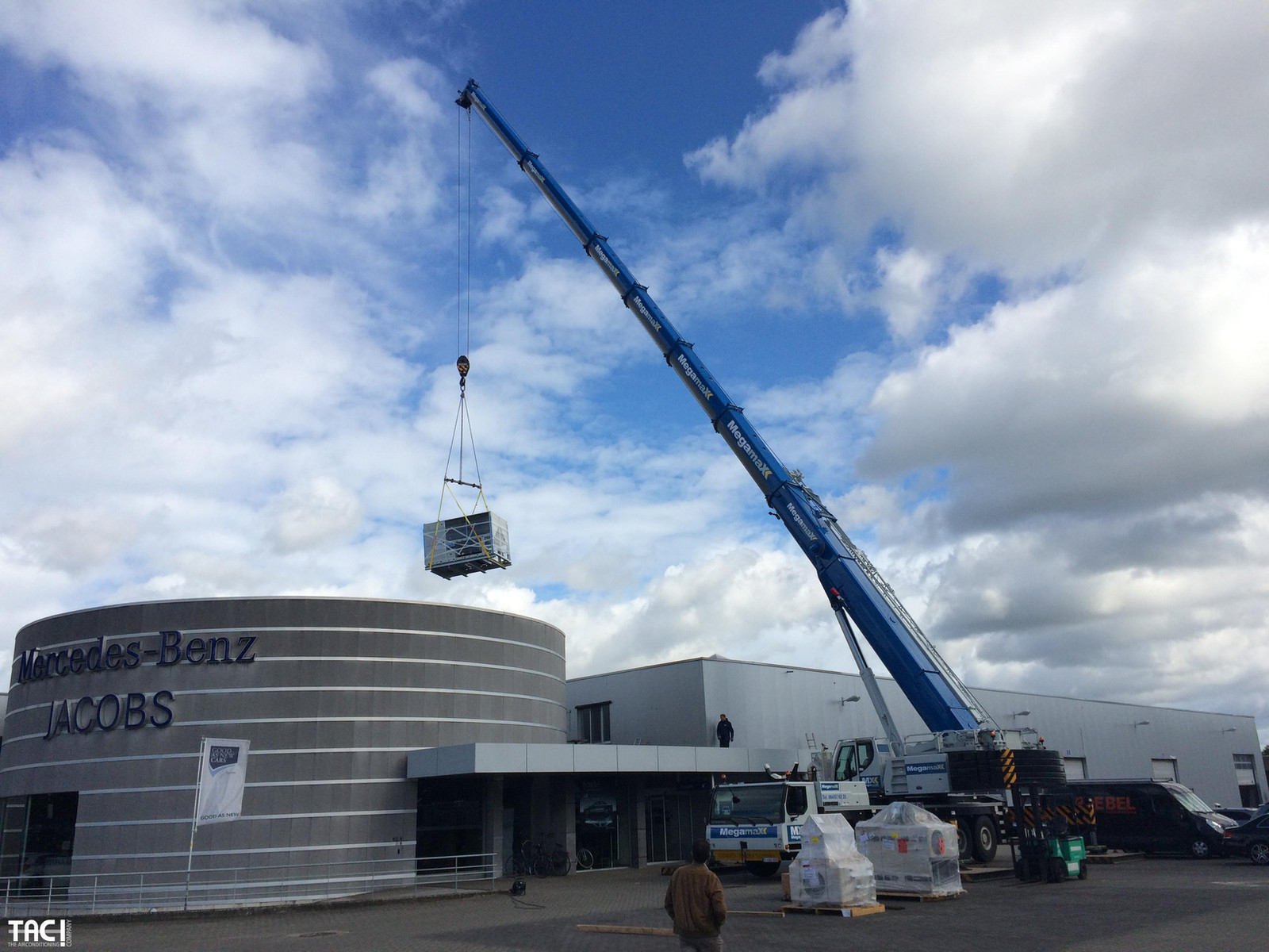 Warmtepomp wordt met een kraan op het dak van de showroom van Garage Hedin getild